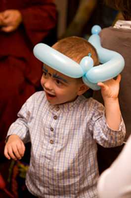 Portrait garçon de 2-3 ans coiffé d'une sculpture de ballons au cours d'une animation d'anniversaire.